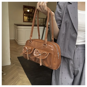 Detail of vintage brown ballet-style shoulder bag with cute bow-tie pockets and glossy finish