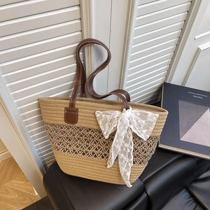 Summer straw tote bag with brown leather handles and decorative white lace bow