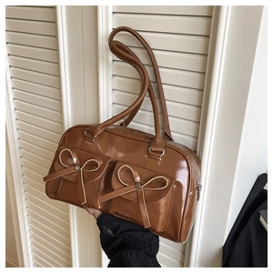 Detail of caramel brown PU leather bag with dual bow-knot flap pockets and top handles