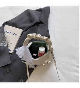 Rangement interne d'un sac à main en dentelle crème avec téléphone et cosmétiques
