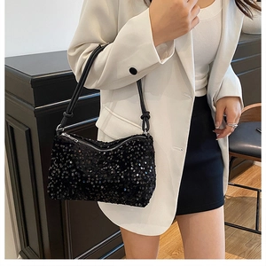 Detailed view of black sequin shoulder bag on model wearing white suit and black skirt