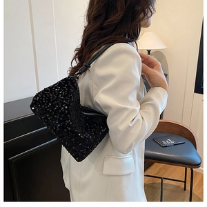 Detail of black sequined shoulder bag featuring a knotted leather strap and half-moon silhouette
