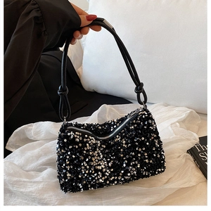 Detail of black sequined shoulder bag with knotted strap and metallic zipper closure
