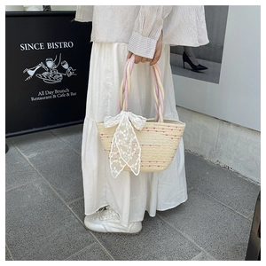 Detail of woven straw tote bag with colorful specks and an embroidered lace bow