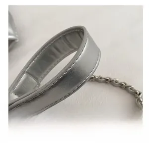 Detail of silver chain strap and metallic PU leather stitching on a fashion crossbody bag