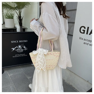 Detail of hand-woven straw tote bag with colorful accents and a large lace bow decoration