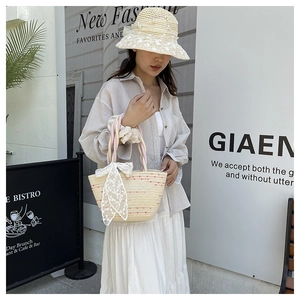 Detail of hand-woven straw tote bag with white lace bow and colorful rope handle