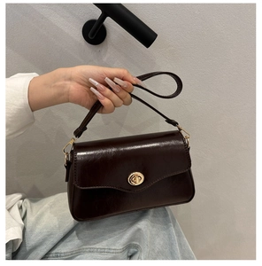 Close-up of deep brown glossy leather handbag with retro gold twist lock and fine strap