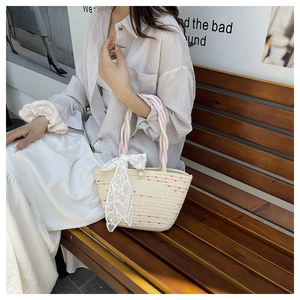 Detalle de bolso bandolera tejido crema con asa trenzada rosa y lazo de encaje