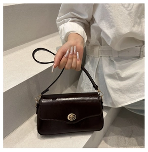 Detail of dark brown leather handbag with gold twist lock and fine shoulder strap