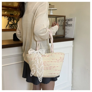 Detail of hand-woven straw tote with white lace bow and elegant pearl accent
