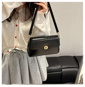 Detail of black patent leather shoulder bag with gold twist lock and elegant rectangular flap