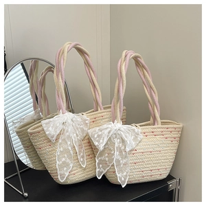 Detail of woven straw tote bag with colorful specks and a large white lace bow accent