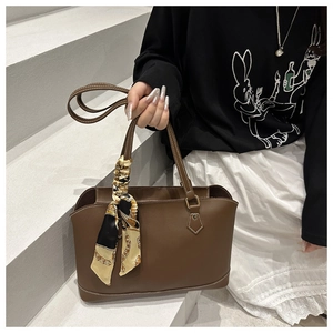 Detail of dark brown leather tote bag with elegant floral scarf on the handle