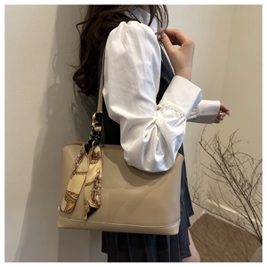 Detail of minimalist cream tote bag with elegant floral silk scarf tied to the handle