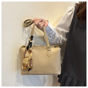 Detail of a beige tote bag with black and yellow silk scarf handle decoration