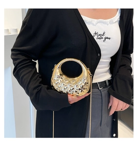 Detail of a gold metallic mini handbag with round handle and quilted texture on a model