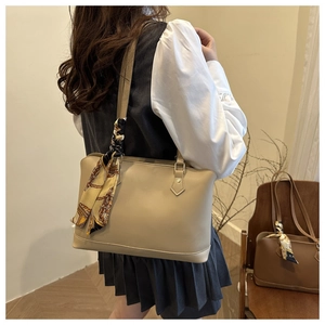 Detail view of large beige tote bag with floral silk scarf on shoulder strap