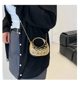 Detail of a semi-circle gold acrylic mini bag with quilted pattern and chain strap