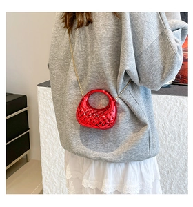 Detail of red quilted mini crossbody bag with golden chain strap on a model