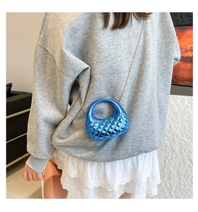 Macro shot of bright blue quilted acrylic mini bag with gold chain and round handle