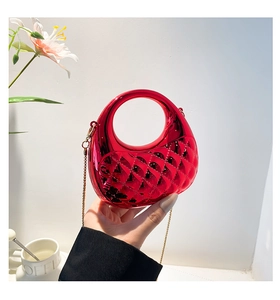 Detail of red quilted patent leather mini bag with curved handle and gold chain strap