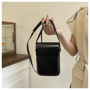 Detail of minimalist black crossbody phone bag with adjustable strap and flap closure