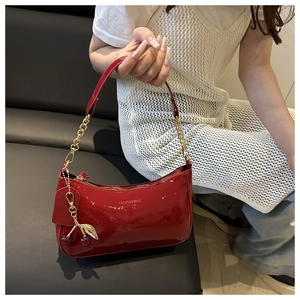Vue détaillée du sac hobo en cuir verni rouge avec breloque cerise et chaîne dorée