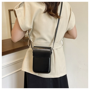 Detalle de un bolso bandolera negro minimalista para móvil con solapa y correa fina