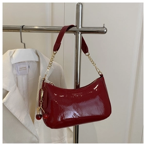 Détail du sac en cuir verni bordeaux avec chaîne dorée et breloque cerise rouge