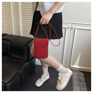 Close-up of a minimalist bright red crossbody bag with smooth leather finish and flap