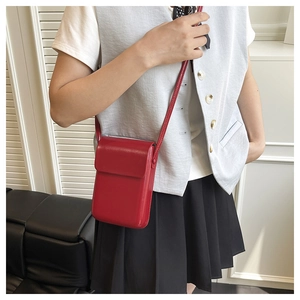 Primer plano de un bolso de hombro vertical rojo de cuero PU para móvil usado por una modelo