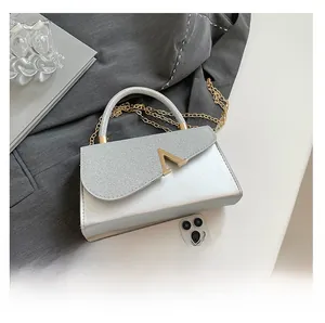 Detail shot of silver glitter crossbody bag with gold V-shaped buckle and metal chain