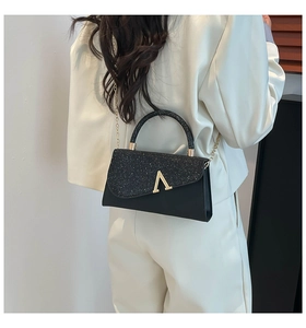 Detail of elegant black glitter evening clutch with golden A-shaped metal clasp and chain
