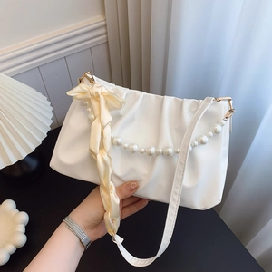 Elegant white pleated cloud bag with pearl chain and silk bow shown in a lifestyle setting