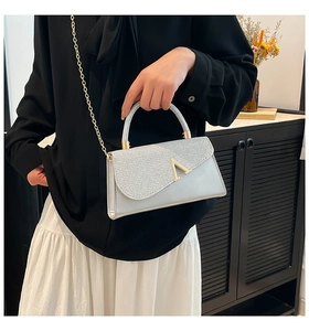 Detail of silver glitter handbag with gold V-shape clasp and chain strap