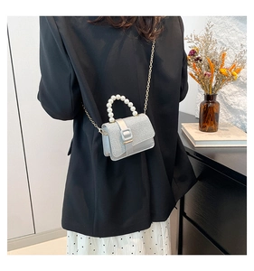 Silver sequin mini crossbody bag with pearl handle worn by model in elegant black suit