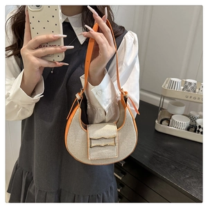 Détail du sac hobo en tissu tissé avec garniture en cuir orange porté par un mannequin