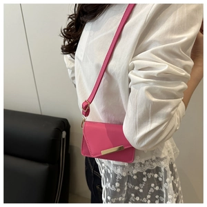 Detail of a bright pink mini crossbody bag with gold metal trim and leather strap