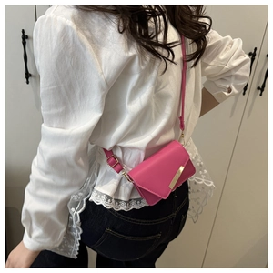 Detailed view of magenta mini envelope bag with gold buckle on a crossbody shoulder strap