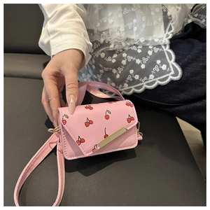 Detailed view of pink crossbody bag featuring cherry print and gold clasp closure