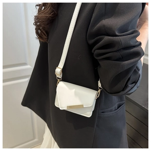 Detailed view of mini white crossbody bag with gold metal trim and adjustable strap