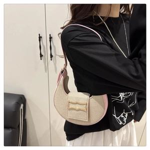 Détail de la bandoulière en cuir rose et du sac croissant en toile sur l'épaule