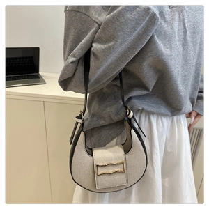 Detail of minimalist two-tone half-moon shoulder bag with golden buckle and woven texture