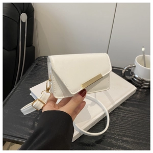 Close-up of white crossbody bag with gold metal buckle and cherry pattern on wooden desk