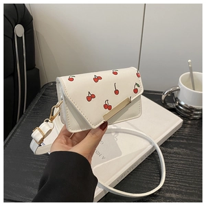 Detail of white mini crossbody bag with red cherry pattern and gold square buckle
