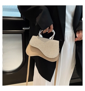 Detail of beige leather crossbody bag with silver sequin flap and geometric metal handle