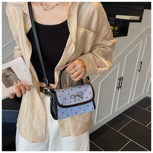 Detail of a light blue bow-knot handbag with black heart prints and stripes