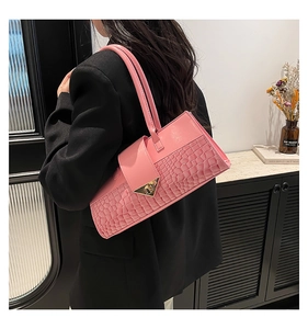 Détail du sac à bandoulière rose effet crocodile avec fermoir métallique triangulaire doré