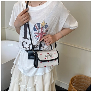 Detail view of white shoulder bag with red bow prints and metallic butterfly clasp
